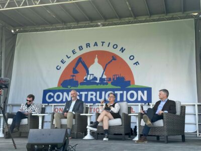 A group of people are on stage participating in a forum about American Infrastructure. 